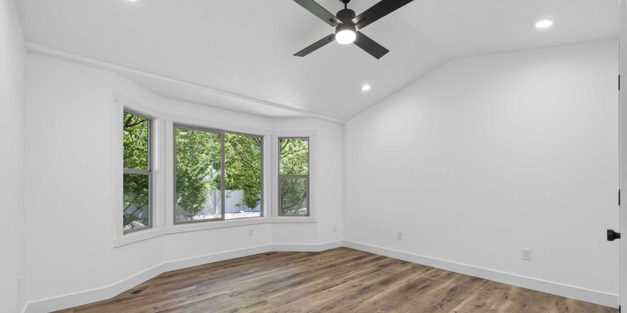 A remodeled interior with a bay window, ceiling fan, and fresh paint by Marshall Homes in Salt Lake City