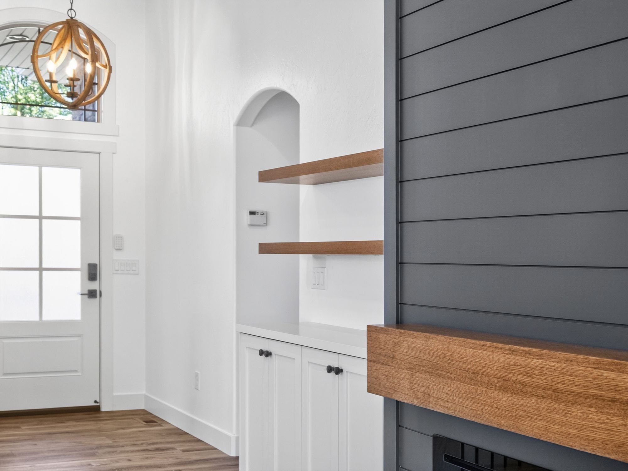 Entryway of a custom home in Herriman, UT with custom storage, lighting, and a window above the door by Marshall Homes