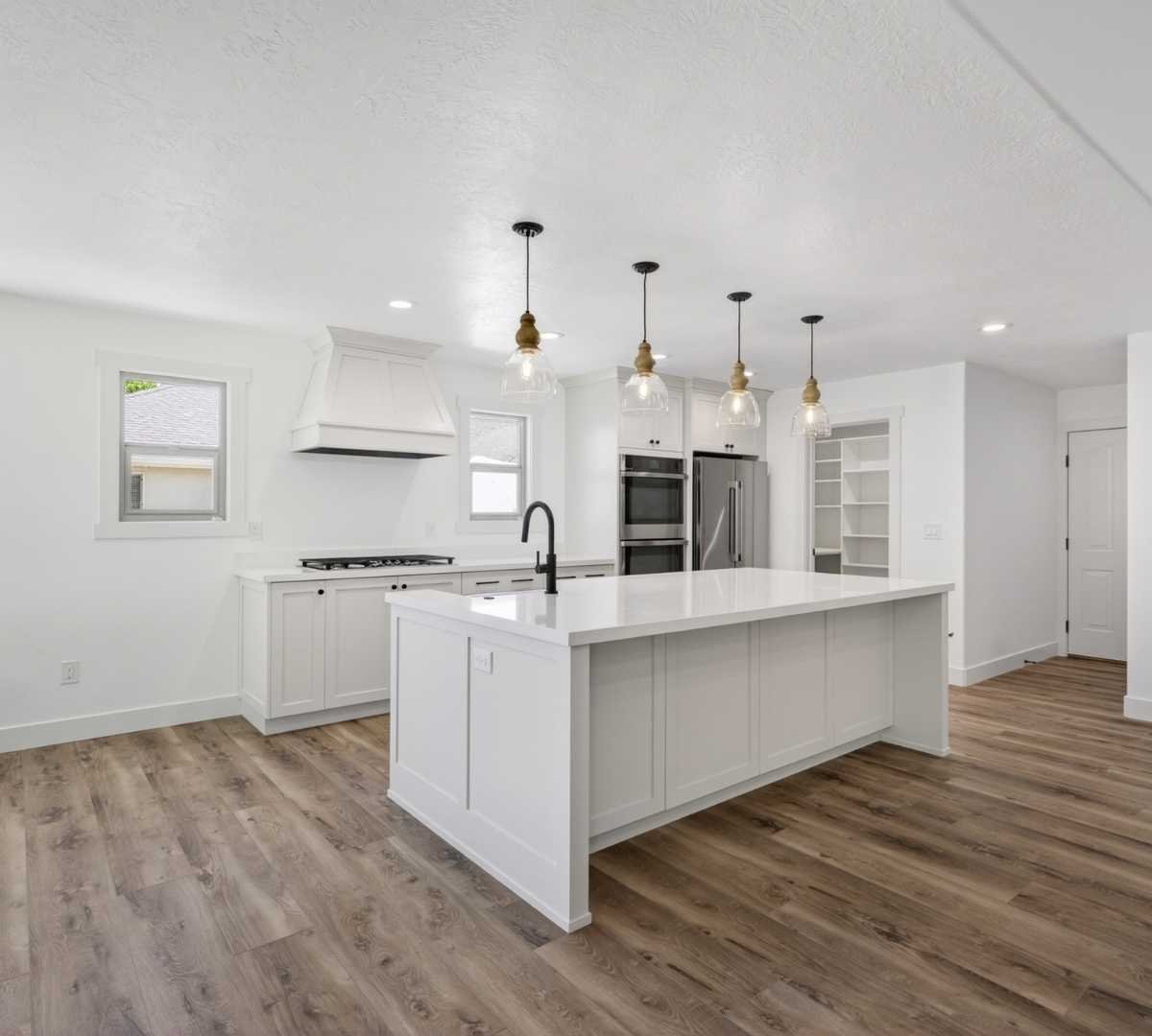 Image of kitchen remodel with large island, pendant lighting, and open layout by Marshall Homes in Herriman, UT