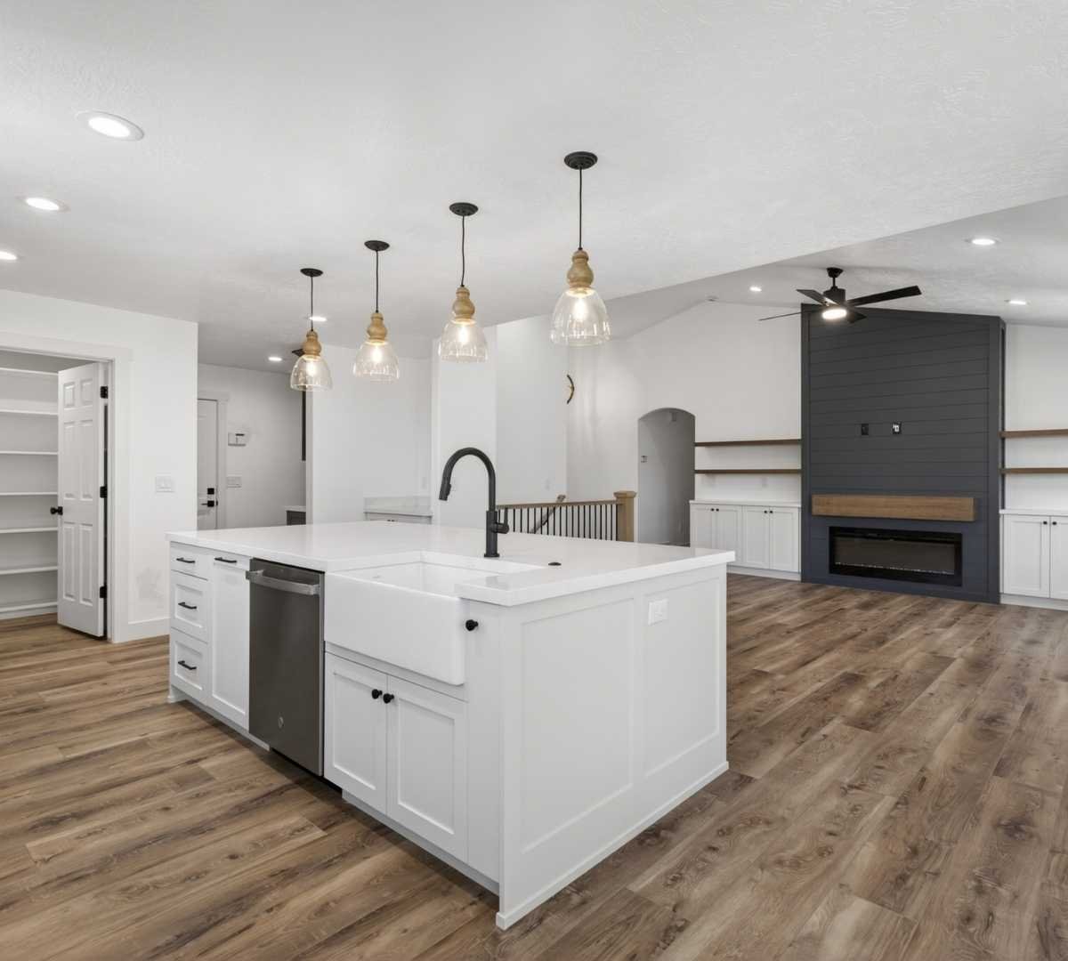 Image of open-concept kitchen remodel with farmhouse sink and fireplace wall by Marshall Homes in Herriman, UT