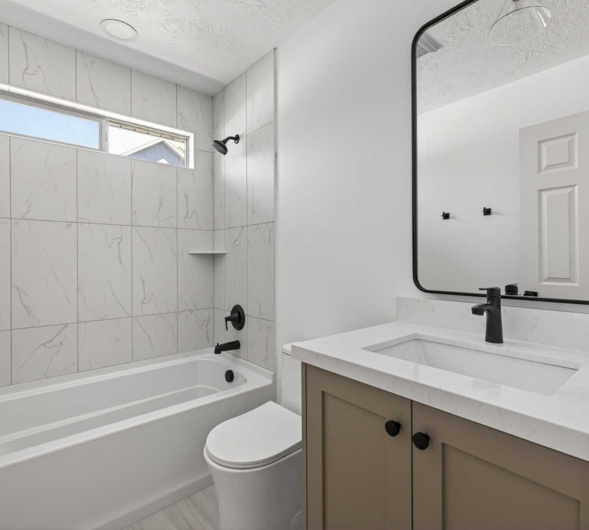 Photo of bathroom remodel with marble-look tile and custom vanity by Marshall Homes in Herriman, UT