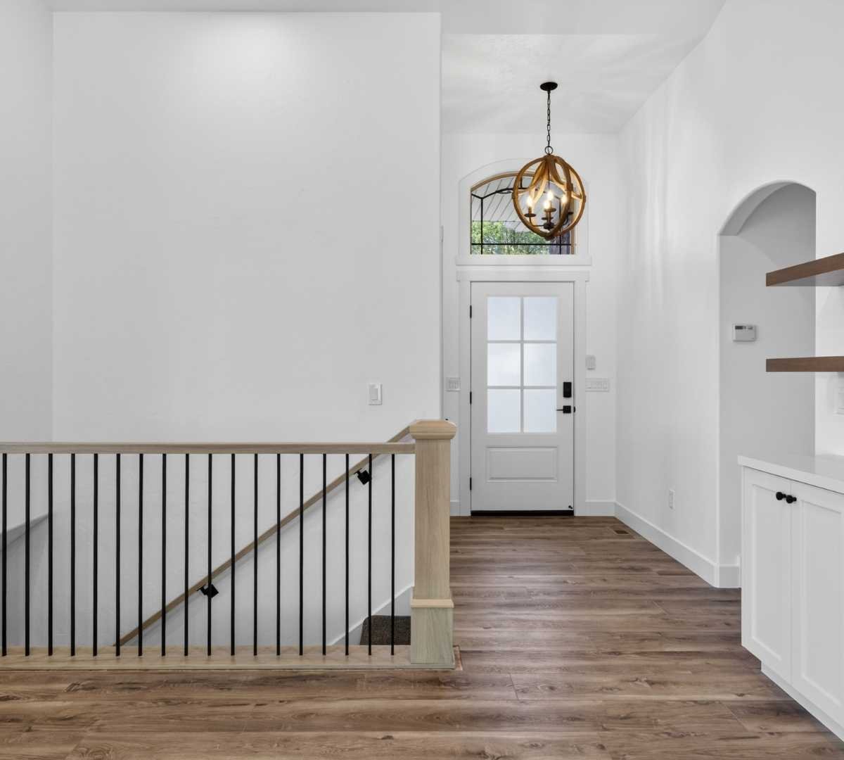 Photo of bright foyer remodel with staircase and designer lighting by Marshall Homes in Herriman, UT