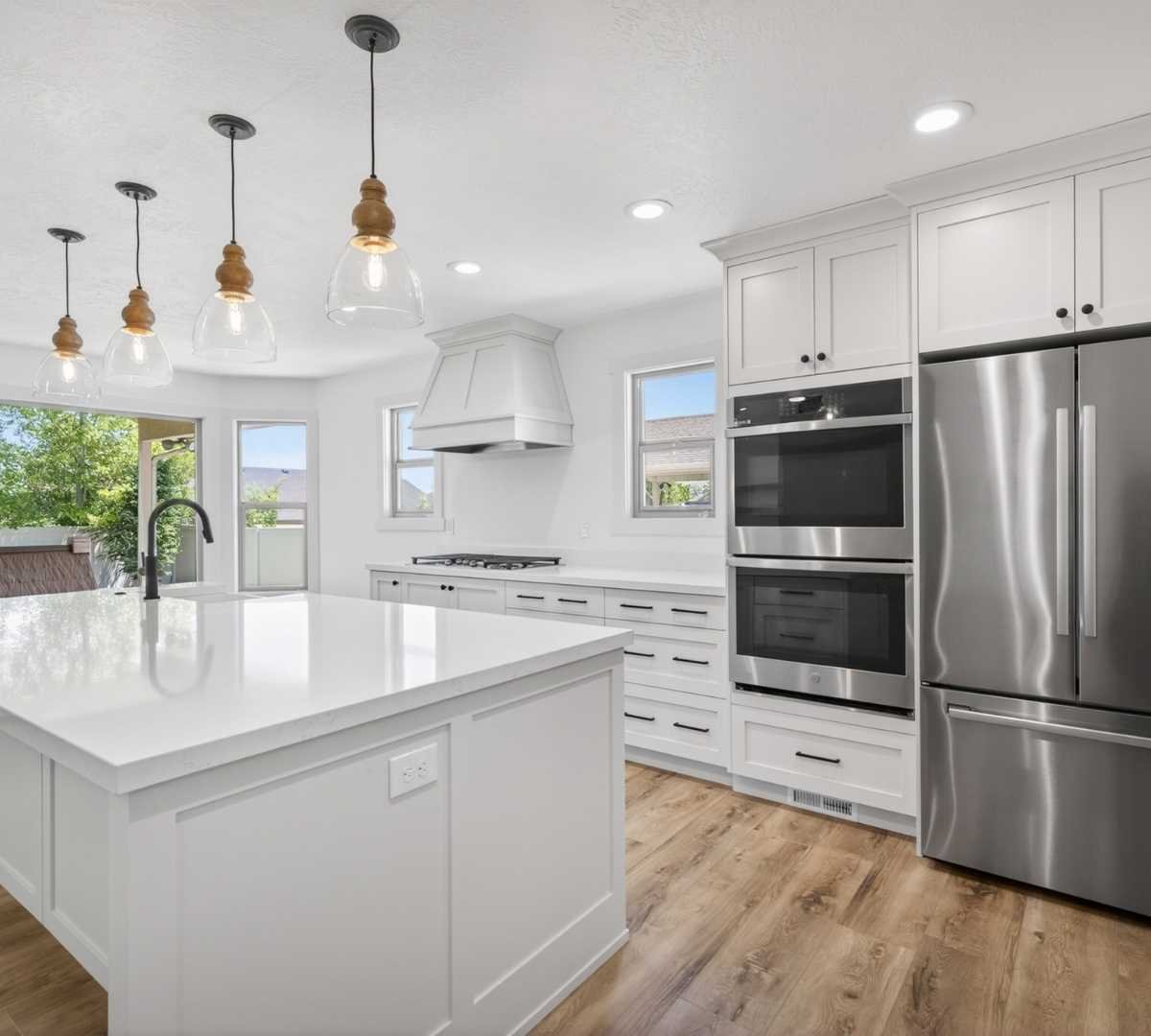 Photo of bright kitchen remodel with double ovens and large island by Marshall Homes in Herriman, UT
